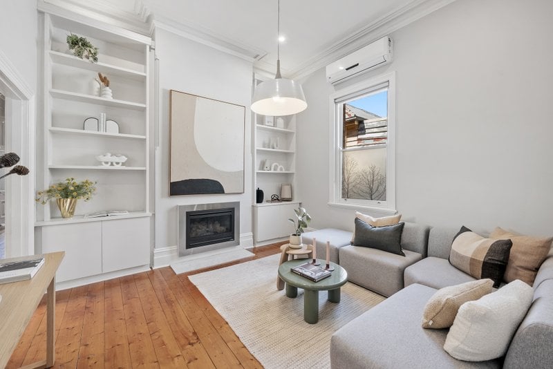 Modern living room with white walls, built-in shelves, fireplace, and contemporary furniture, bright natural light.