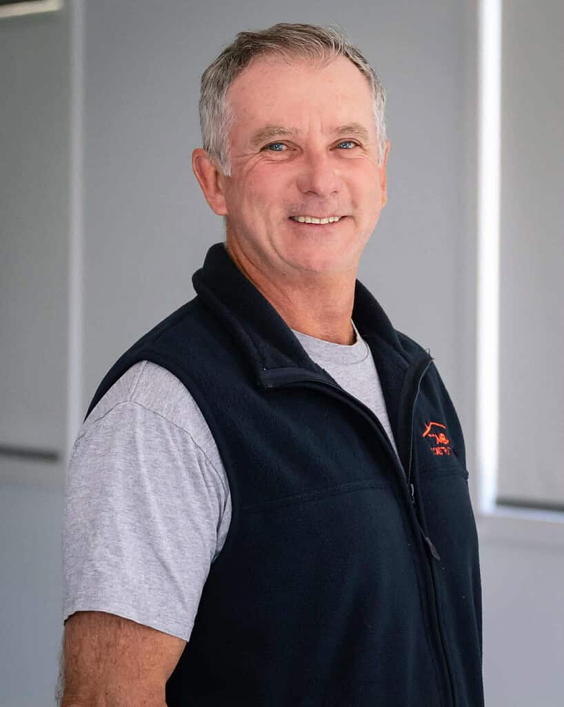 Construction professional smiling in workwear at construction site.