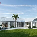 Beautiful white house with a metal roof, outdoor seating, and pool, set in a lush green yard.