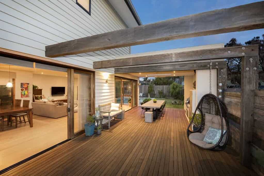 Outdoor deck with wooden flooring, seating area, and swing for relaxing.